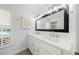Bright bathroom with double vanity, marble countertop, dark hardware and a large mirror at 572 Commonwealth Ln, Sarasota, FL 34242