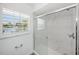 Bright bathroom with marble walk-in shower, glass door, and window with shutters at 572 Commonwealth Ln, Sarasota, FL 34242