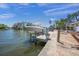 Waterfront property featuring a boat lift, dock, and outdoor seating area at 572 Commonwealth Ln, Sarasota, FL 34242
