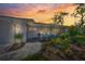 Charming front exterior with cozy seating and lush landscaping at sunset at 572 Commonwealth Ln, Sarasota, FL 34242