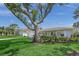 Charming home with lush landscaping, mature trees, and a well-maintained front yard at 572 Commonwealth Ln, Sarasota, FL 34242