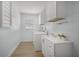 Well-lit laundry room featuring modern white cabinets, sink, and washer-dryer units at 572 Commonwealth Ln, Sarasota, FL 34242