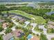 Picturesque aerial view featuring backyard pools, a golf course, ponds, and lush landscaping in this community at 664 Planters Manor Way, Bradenton, FL 34212