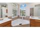 Bright bathroom with soaking tub, wood cabinets, dual sinks and arched windows at 664 Planters Manor Way, Bradenton, FL 34212