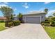 Long driveway leads up to a two-car garage, complimented by manicured landscaping and beautiful blue skies at 664 Planters Manor Way, Bradenton, FL 34212