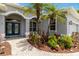 Close-up of a home's front entrance with garden, arched entry, blue double doors, and seating at 664 Planters Manor Way, Bradenton, FL 34212