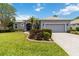 Charming one-story home featuring a well-manicured lawn, beautiful landscaping, and an attached two-car garage at 664 Planters Manor Way, Bradenton, FL 34212