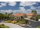 Beautiful exterior of The River Club with lush landscaping, a roundabout, and palm trees under a sunny blue sky at 706 Misty Pond Ct, Bradenton, FL 34212