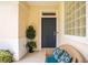 Charming front porch with a blue door, glass block window, and a cozy wicker chair with patterned pillows at 706 Misty Pond Ct, Bradenton, FL 34212