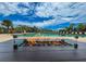 Resort-style pool area with a modern fire pit, lounge chairs, palm trees, and clear blue skies at 706 Misty Pond Ct, Bradenton, FL 34212