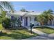 Charming single-story home featuring a white tiled roof, bright purple door and shutters, and lush landscaping at 730 Spanish S Dr # 99, Longboat Key, FL 34228