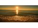 Tranquil ocean view at sunset, featuring golden sunlight reflecting on the calm water and gentle waves at 730 Spanish S Dr # 99, Longboat Key, FL 34228