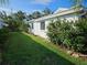 Well-maintained side yard with lush green grass, flowering bushes, and tropical landscaping against the white exterior at 730 Spanish S Dr # 99, Longboat Key, FL 34228