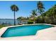 Backyard pool boasts waterfront views and a pristine blue finish, surrounded by lush greenery at 7614 Peninsular Dr, Sarasota, FL 34231