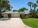 Well-maintained home with a wide driveway, a manicured lawn, and professional landscaping at 7614 Peninsular Dr, Sarasota, FL 34231