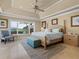 Spacious bedroom with tray ceiling, ceiling fan, water view, and sitting area with a chair at 7614 Peninsular Dr, Sarasota, FL 34231