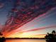 Dramatic sunset featuring vibrant clouds and calm waters, offering a serene and breathtaking view at 7614 Peninsular Dr, Sarasota, FL 34231