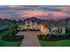 Elegant home with a brick paved driveway, manicured lawn, a two-car garage and lush landscaping at sunset at 7838 Bowspirit Way, Lakewood Ranch, FL 34202