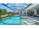 Sparkling pool and spa with lounge chairs, set within a screened enclosure, and lush tropical landscaping at 7838 Bowspirit Way, Lakewood Ranch, FL 34202