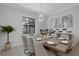 Elegant dining room with modern chandelier, large windows, and decorative artwork at 805 Padua Ct, Nokomis, FL 34275