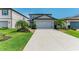Landscaped front yard with palm trees and a paved driveway leading to a two-car garage at 8940 Royal River Cir, Parrish, FL 34219