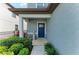 Cozy front porch with a dark blue front door, tasteful decor, and manicured shrubbery at 8940 Royal River Cir, Parrish, FL 34219