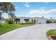 Beautifully landscaped home featuring lush greenery, a circular driveway, and a manicured lawn at 965 E Gondola Dr, Venice, FL 34293