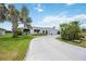 Inviting curb appeal with a circular driveway, mature palm trees, and lush green lawn at 965 E Gondola Dr, Venice, FL 34293