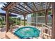 Relaxing screened-in patio featuring a spa with a wooden pergola overhead at 965 E Gondola Dr, Venice, FL 34293