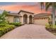 Single-Gathering home featuring an arched entryway, lush landscaping and a long driveway at 11022 Pine Lilly Pl, Lakewood Ranch, FL 34202