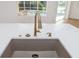 Close-up of kitchen sink with bronze faucet and soap dispenser; view to pool outside kitchen window at 11022 Pine Lilly Pl, Lakewood Ranch, FL 34202