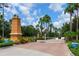 Gated community entrance with brick pavers, a guard house, lush landscaping, and palm trees at 11794 Forest Park Cir, Bradenton, FL 34211