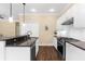 Modern kitchen boasts sleek white cabinetry, stainless steel appliances, and granite countertops with dark wood flooring at 11794 Forest Park Cir, Bradenton, FL 34211