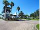 Community entrance with lush landscaping, brick drive and towering palms under a blue sky at 1241 Riverscape St # B, Bradenton, FL 34208