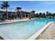 Large community pool with plenty of lounging chairs and palm trees by the clubhouse at 1241 Riverscape St # B, Bradenton, FL 34208