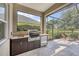 Modern outdoor kitchen with granite countertops, a stainless steel grill, and scenic views of the backyard at 12908 Crystal Clear Pl, Bradenton, FL 34211