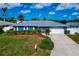 Charming blue single-story home with a grey metal roof, manicured lawn, and two-car garage at 1312 73Rd Nw St, Bradenton, FL 34209