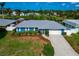 Beautiful single-story home with a blue exterior, metal roof, and lush landscaping near the lake at 1312 73Rd Nw St, Bradenton, FL 34209
