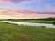Scenic view of the lush green golf course with a tranquil lake and a colorful sky at 17118 Vardon Ter # 404, Bradenton, FL 34211