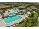 Aerial view of a community pool featuring a waterfall, lounge chairs, umbrellas, and lush tropical landscaping at 17118 Vardon Ter # 404, Bradenton, FL 34211