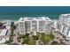 Aerial view of a beachfront condo building surrounded by palm trees and sandy beach at 1800 Benjamin Franklin Dr # B1009, Sarasota, FL 34236