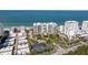 Aerial view of a beachfront condo building with tennis courts, lush landscaping, and beach access at 1800 Benjamin Franklin Dr # B1009, Sarasota, FL 34236