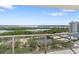 The balcony features glass railings with stunning views of the water, tennis courts, and nearby cityscape at 1800 Benjamin Franklin Dr # B1009, Sarasota, FL 34236
