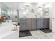 Marble-floored bathroom features dual sinks, modern lighting fixtures, and mirrored walls, with a view of the bathtub at 1800 Benjamin Franklin Dr # B1009, Sarasota, FL 34236
