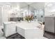 Corner bathtub surrounded by mirrored walls, with dual sinks and marble countertops in an elegant and spacious bathroom at 1800 Benjamin Franklin Dr # B1009, Sarasota, FL 34236