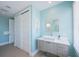 This bathroom showcases a modern vanity, square mirror, and linen closet with a refreshing aqua color scheme at 2201 Avenue C, Bradenton Beach, FL 34217