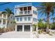 Stunning exterior of a modern beach home featuring multi-level balconies and a two-car garage surrounded by palm trees at 2201 Avenue C, Bradenton Beach, FL 34217