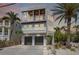 Beautiful three-story beach home featuring a two-car garage, covered balconies, and tropical landscaping at 2201 Avenue C, Bradenton Beach, FL 34217