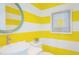 Stylish powder room with yellow and white striped walls, vessel sink, and decorative mirror at 2201 Avenue C, Bradenton Beach, FL 34217