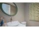Charming powder room with a round mirror, whimsical artwork, and elegant white sink at 2201 Avenue C, Bradenton Beach, FL 34217